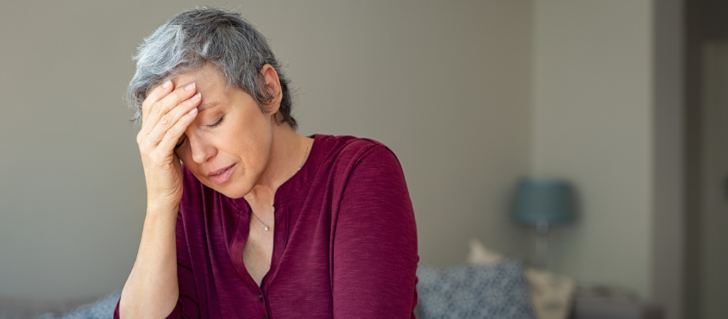 Woman struggling with memory loss as she holds her hand to her head.